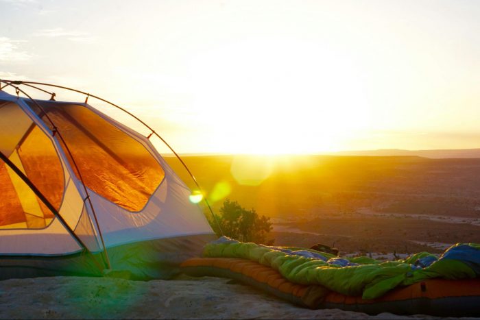 A camping scene featuring a tent and a sleeping bag positioned on a rugged rock, ideal for outdoor enthusiasts.
