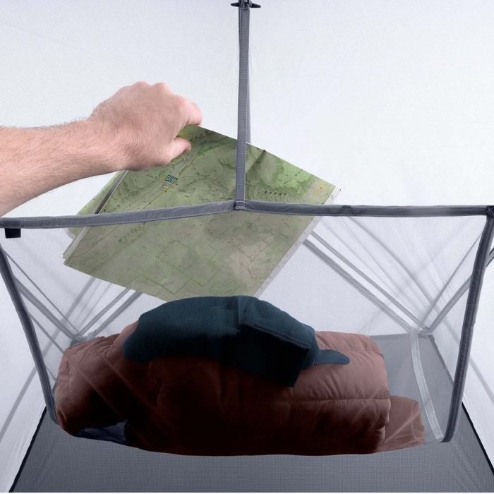A hand placing a map into a gear loft into a tent.