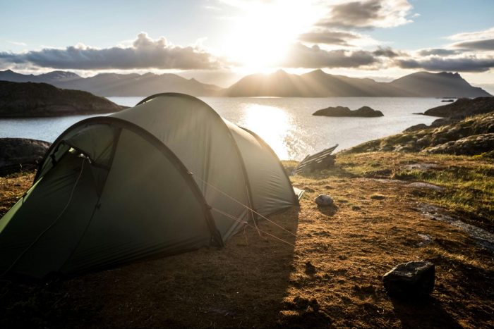 A tent is set up on a hill, providing a scenic view of a lake below.