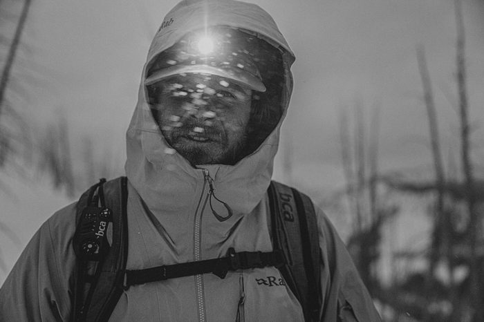 Man wearing a Rab jacket with a head torch looking at the camera